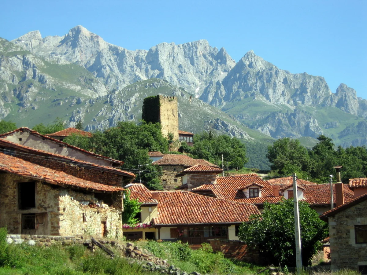 Pueblos bonitos Cantabria: Pueblo de Mogrovejo con la torre medieval y montañas de Cantabria al fondo