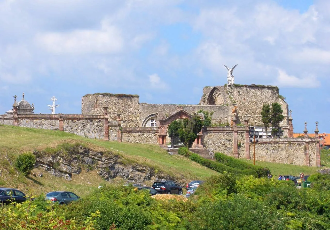 Entrada del cementerio de Comillas y escultura del ángel sobre los muros de la antigua iglesia